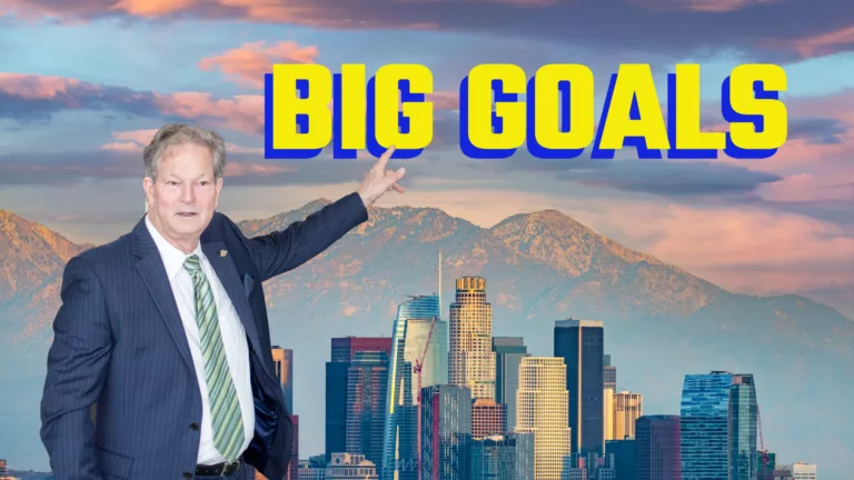 William Osgood pointing to text that reads "Big Goals". Los Angeles skyline in the background